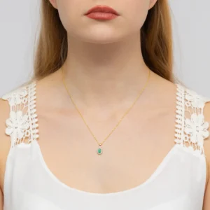 Pandantiv din aur galben 14K cu smarald și diamante purtat la gât, pe un model.
