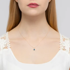 Descoperă piatra zodiei Gemeni și bijuteriile care le reflectă personalitatea 14 Pandantiv aur roz Celeste cu topaz London Blue și diamant, purtat de o femeie.