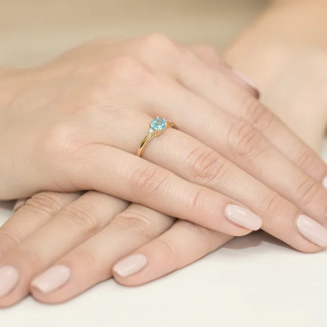 Inel Aur 14K cu Topaz albastru și diamante, purtat pe mâna unei femei.